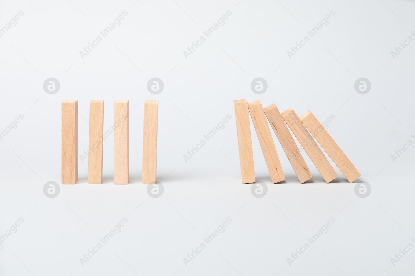 Photo of Domino effect. Wooden blocks falling on light background