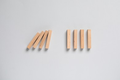 Photo of Domino effect. Wooden blocks on light background, flat lay