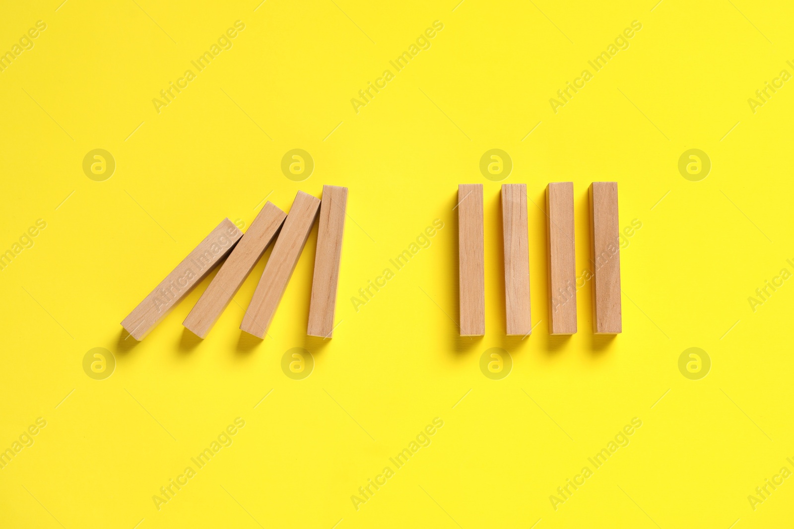 Photo of Domino effect. Wooden blocks on yellow background, flat lay