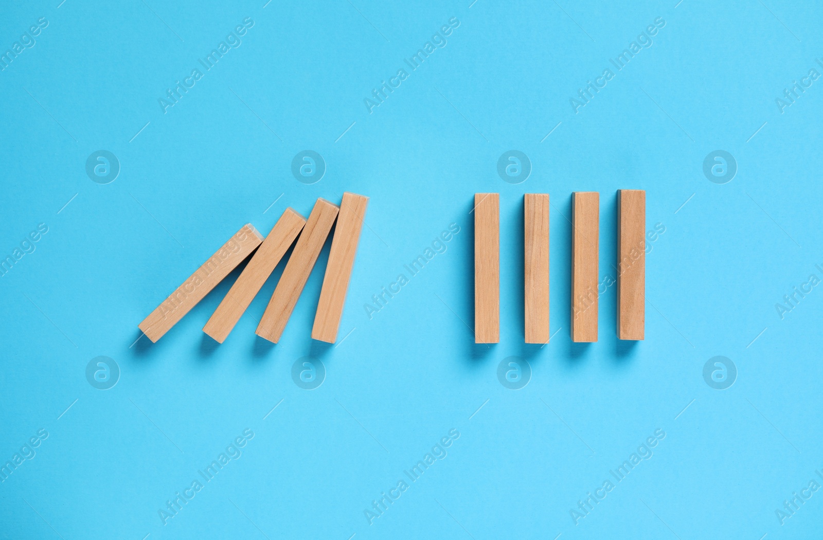 Photo of Domino effect. Wooden blocks on light blue background, flat lay