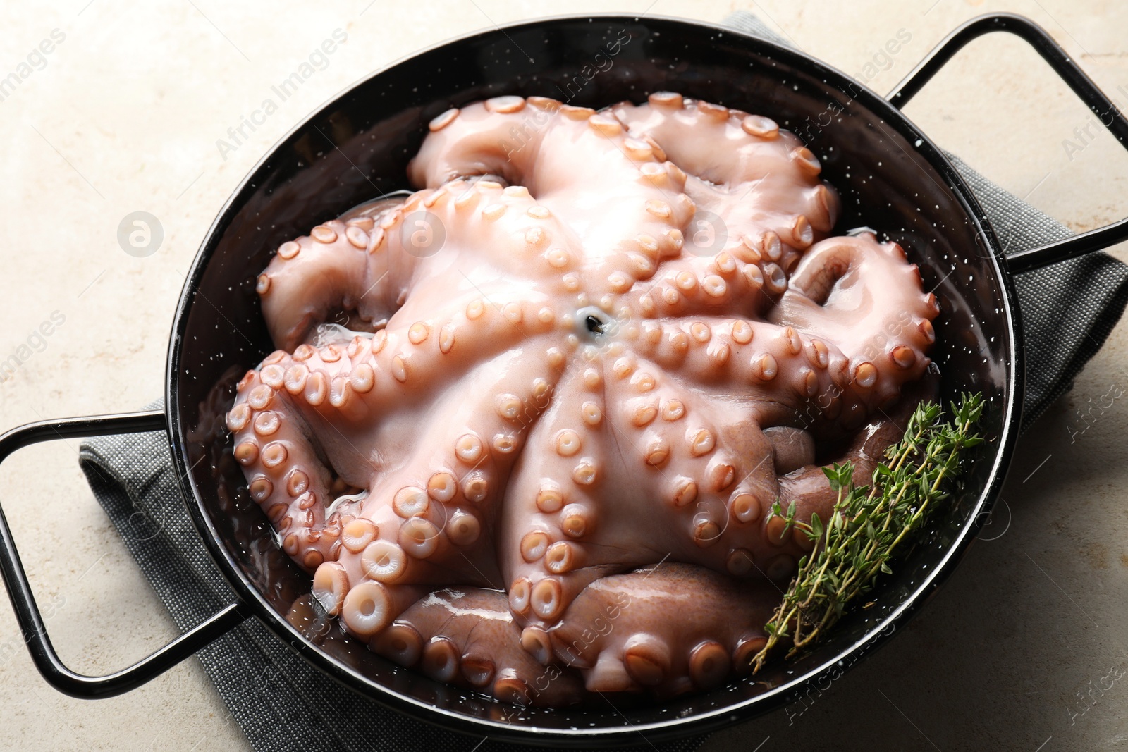 Photo of Fresh raw octopus and thyme in frying pan on grey table, closeup