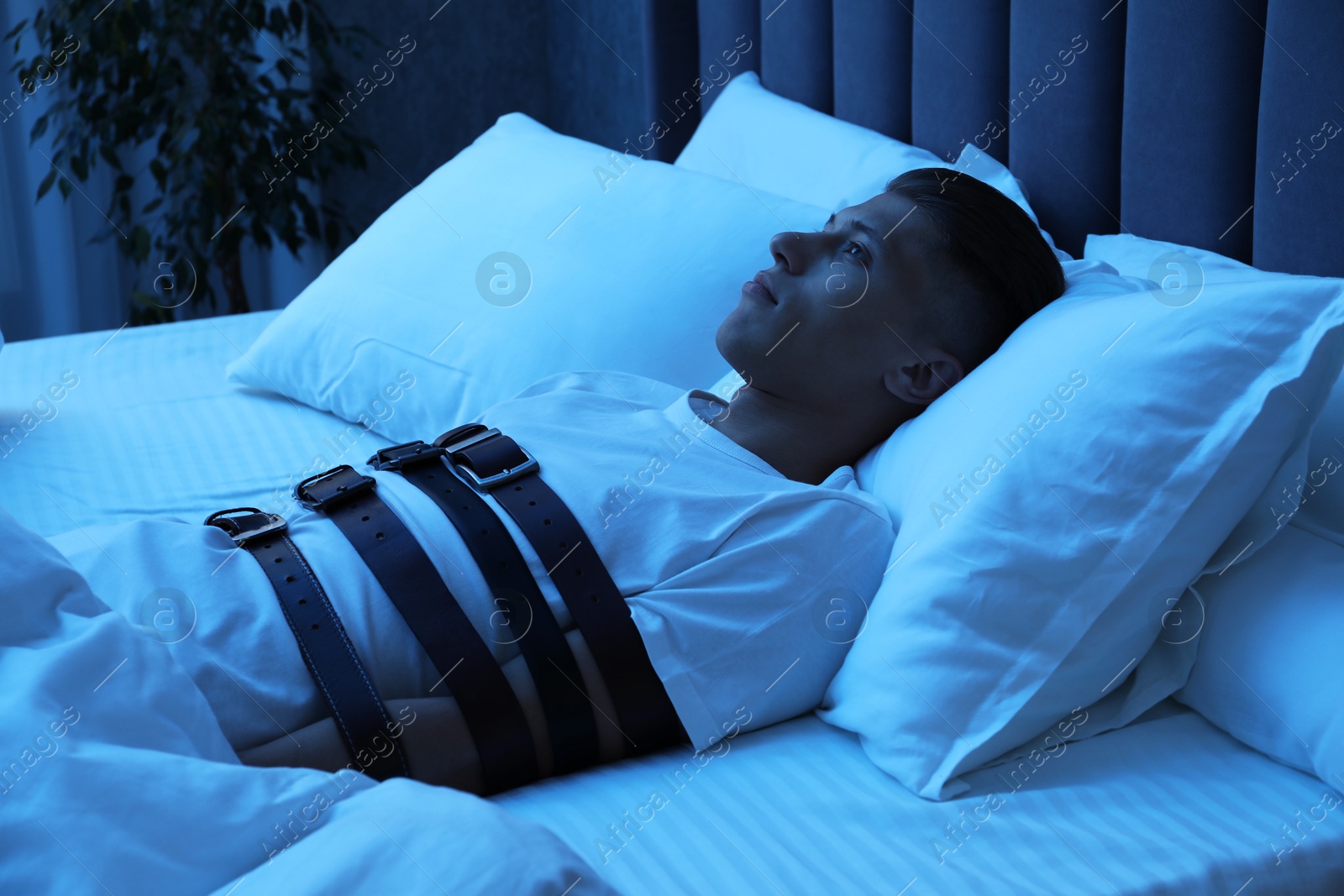 Photo of Sleepwalker fastened with belts lying in bed