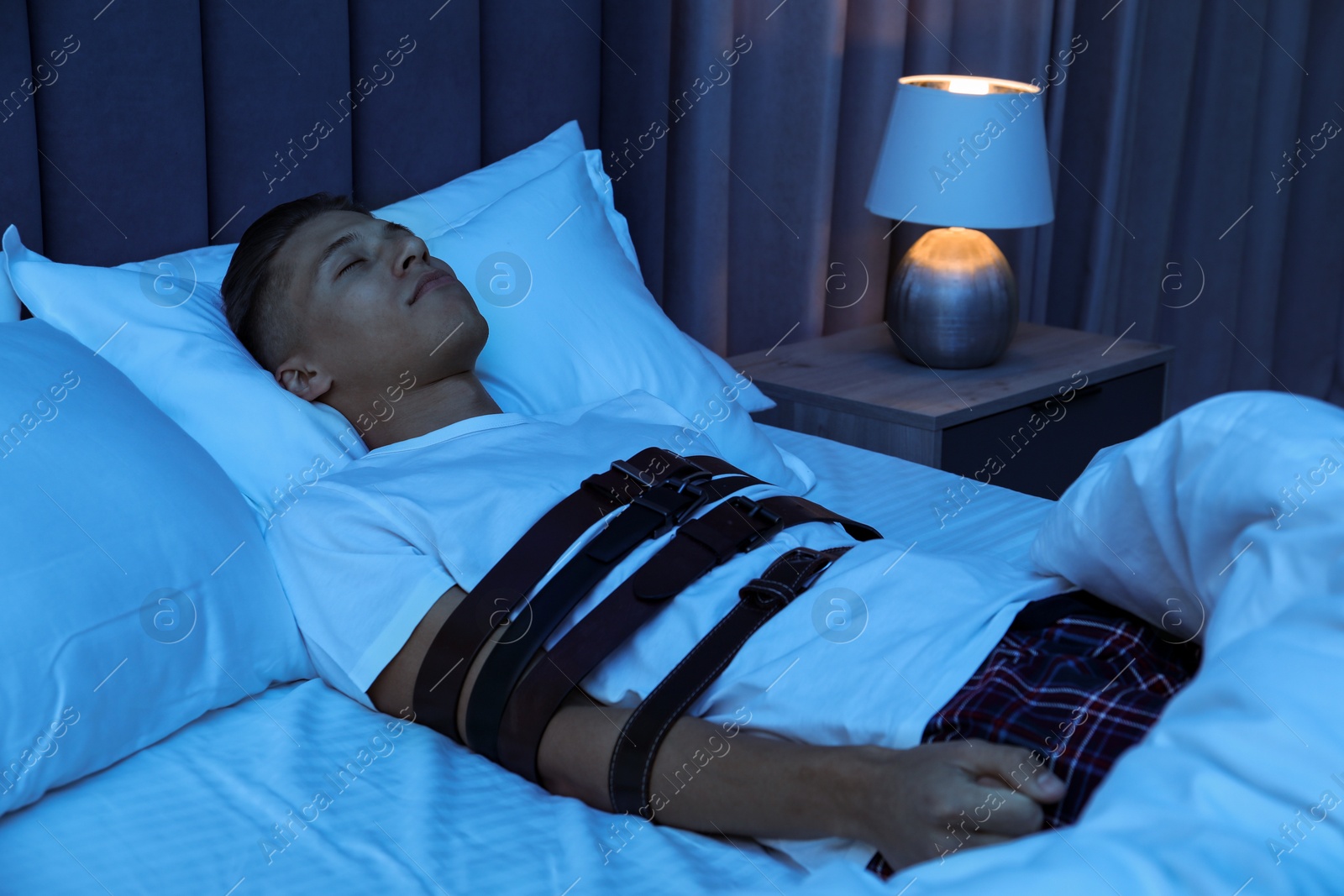 Photo of Sleepwalker fastened with belts lying on bed