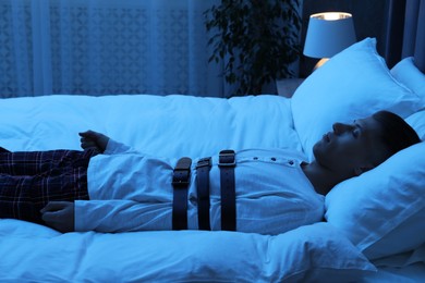 Photo of Sleepwalker fastened with belts lying on bed