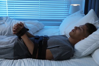 Photo of Sleepwalker fastened with belts lying on bed