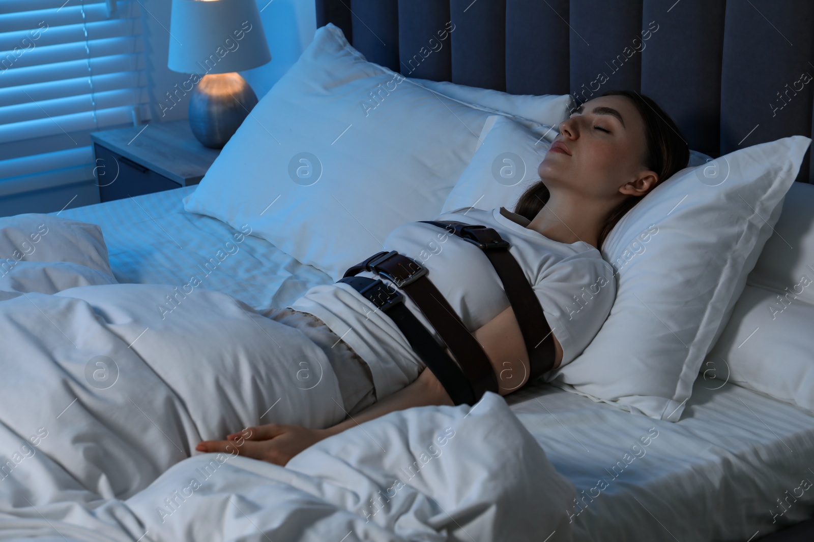 Photo of Sleepwalker fastened with belts lying in bed