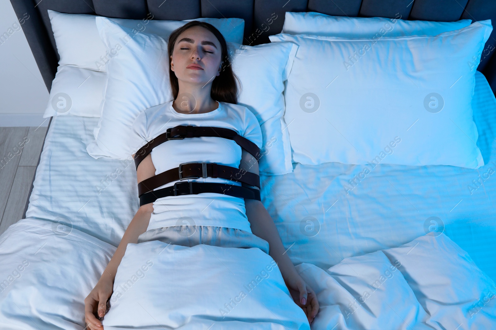 Photo of Sleepwalker fastened with belts lying in bed, above view