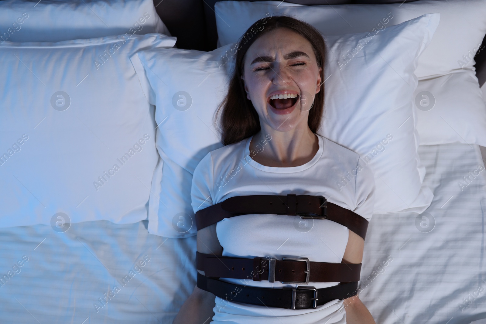 Photo of Woman in sleepwalking condition screaming on bed, top view