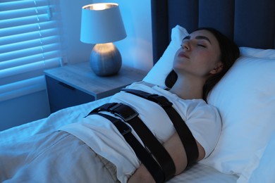 Photo of Sleepwalker fastened with belts lying on bed