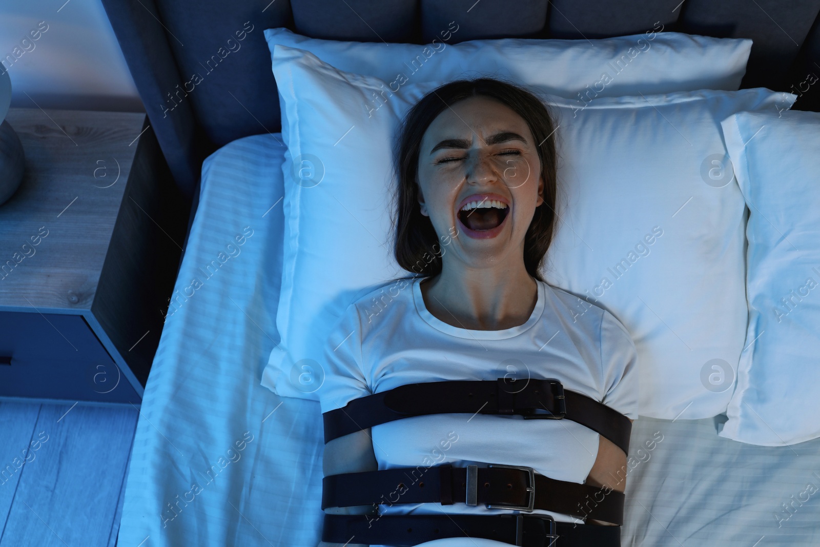 Photo of Woman in sleepwalking condition screaming on bed, top view