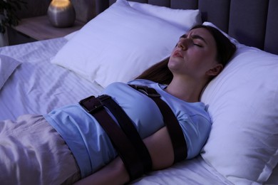 Photo of Sleepwalker fastened with belts lying on bed