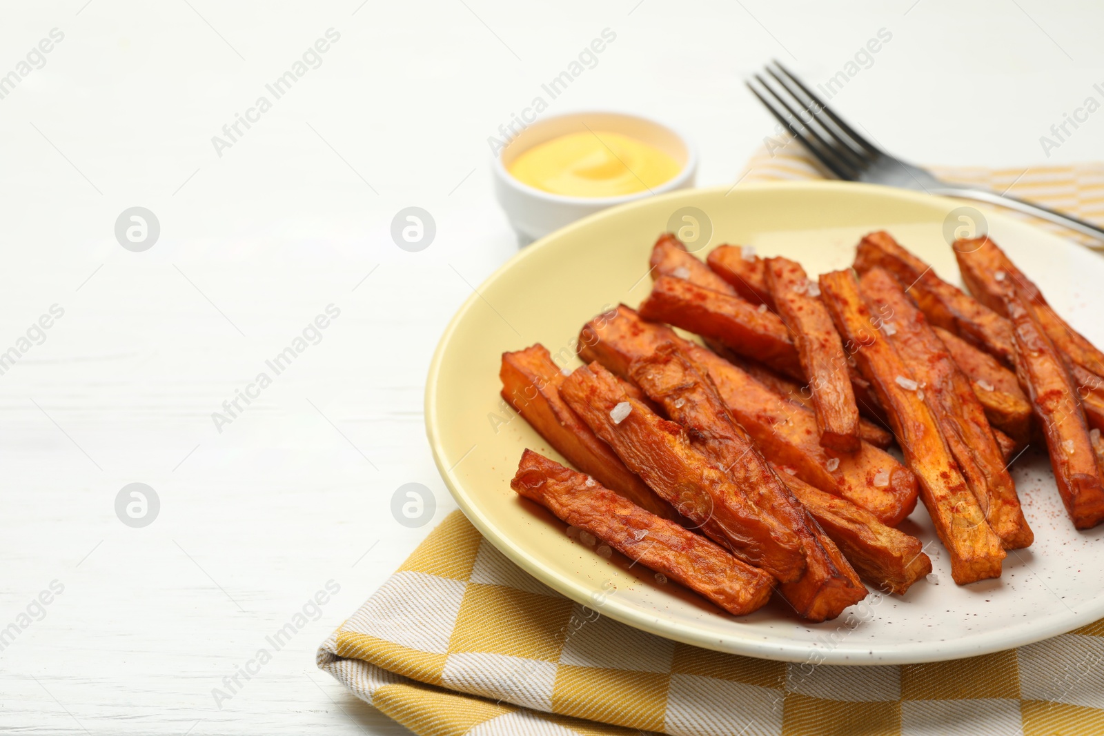 Photo of Delicious sweet potato fries and sauce on white wooden table, closeup. Space for text