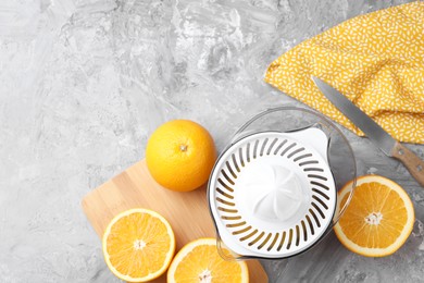 Photo of Plastic juicer, oranges and knife on grey table, top view. Space for text