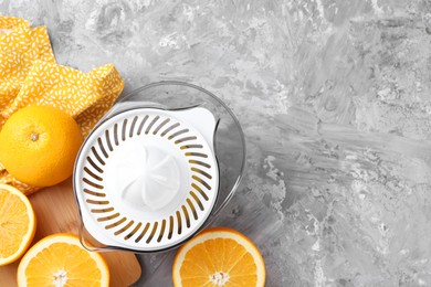 Photo of Plastic juicer and oranges on grey table, top view. Space for text