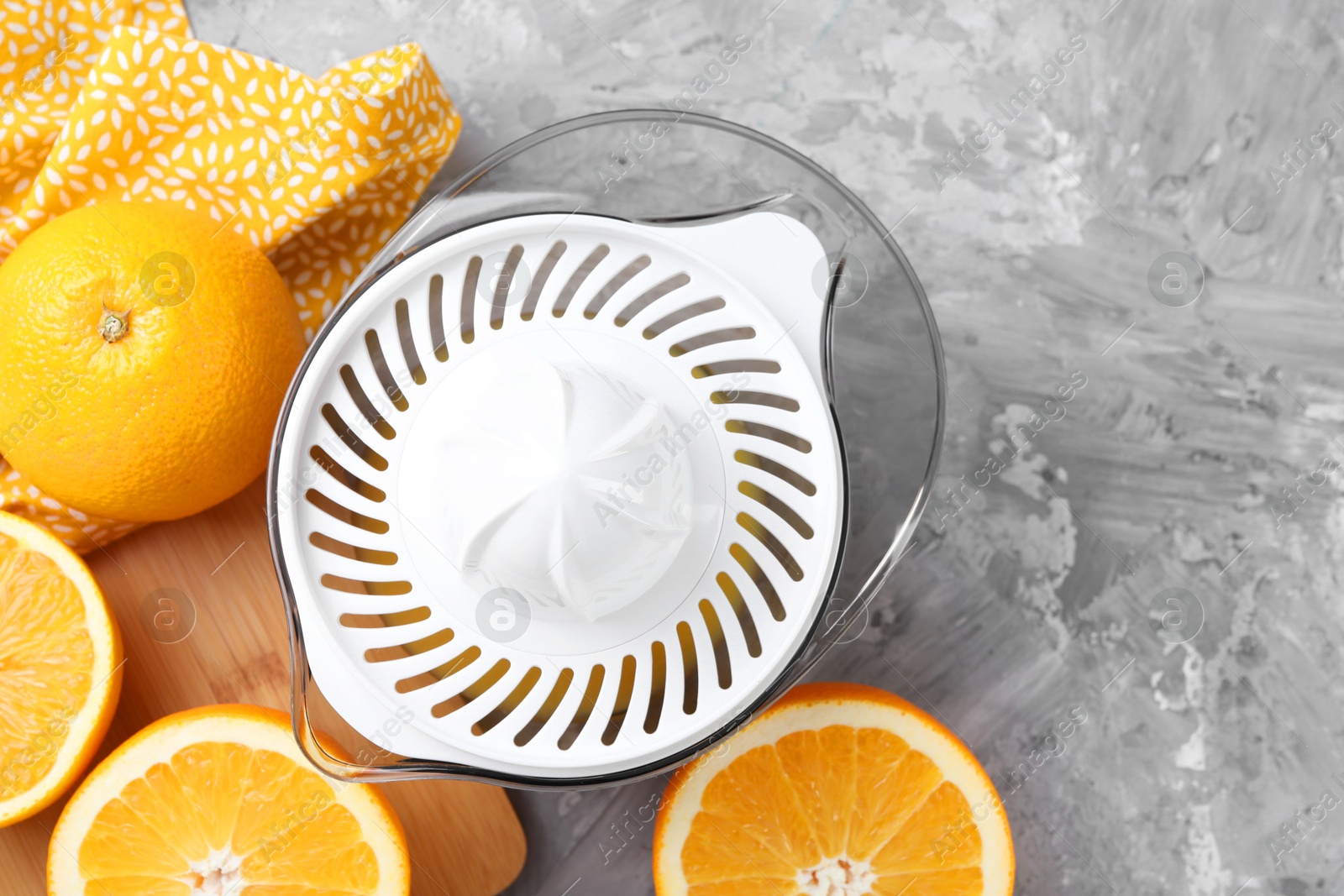 Photo of Plastic juicer and oranges on grey table, top view