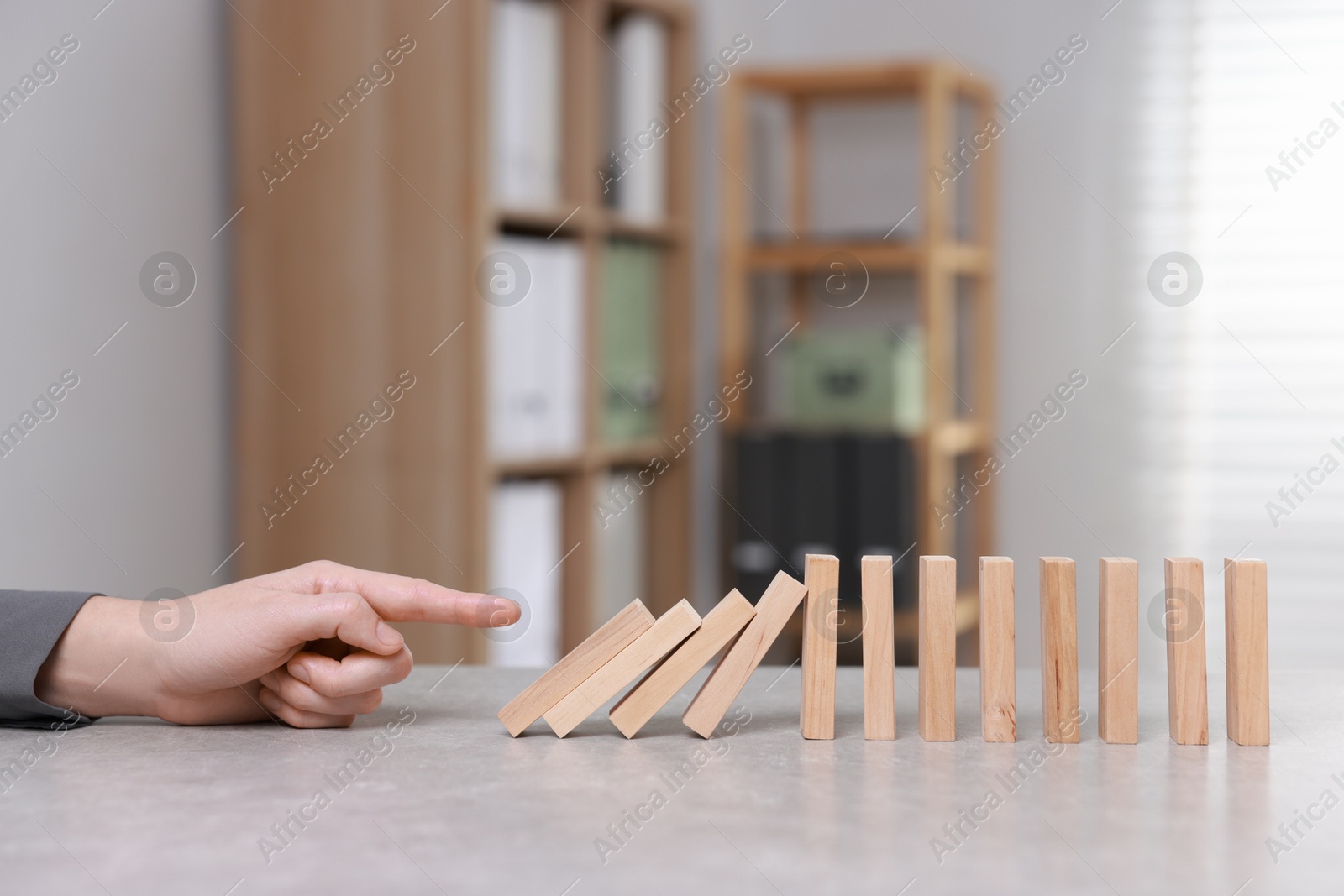 Photo of Domino effect. Woman pushing wooden blocks at table, closeup