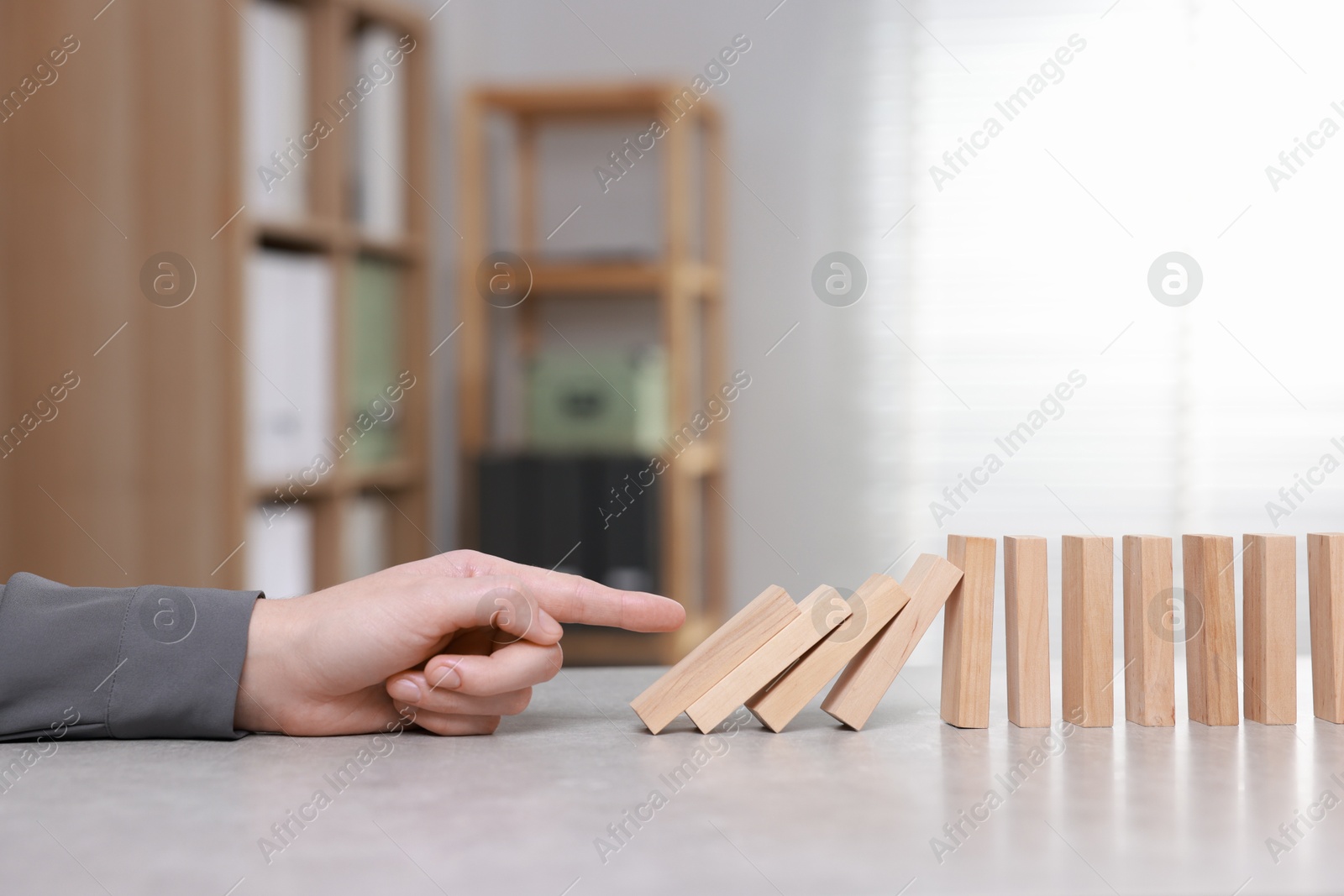 Photo of Domino effect. Woman pushing wooden blocks at table, closeup