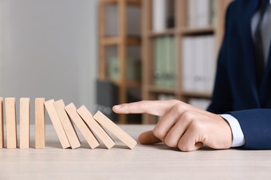 Photo of Domino effect. Man pushing wooden blocks at table, closeup