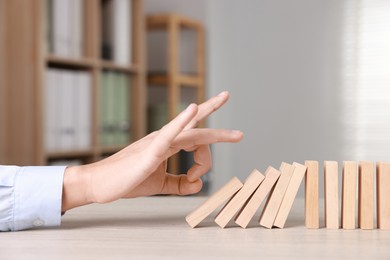 Photo of Domino effect. Man pushing wooden blocks at table, closeup