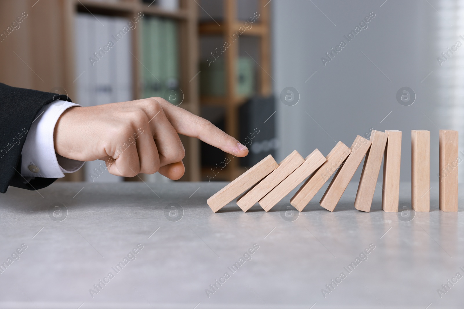 Photo of Domino effect. Man pushing wooden blocks at table, closeup