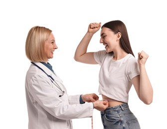 Happy woman lost weight. Nutritionist measuring patient's waist with tape on white background