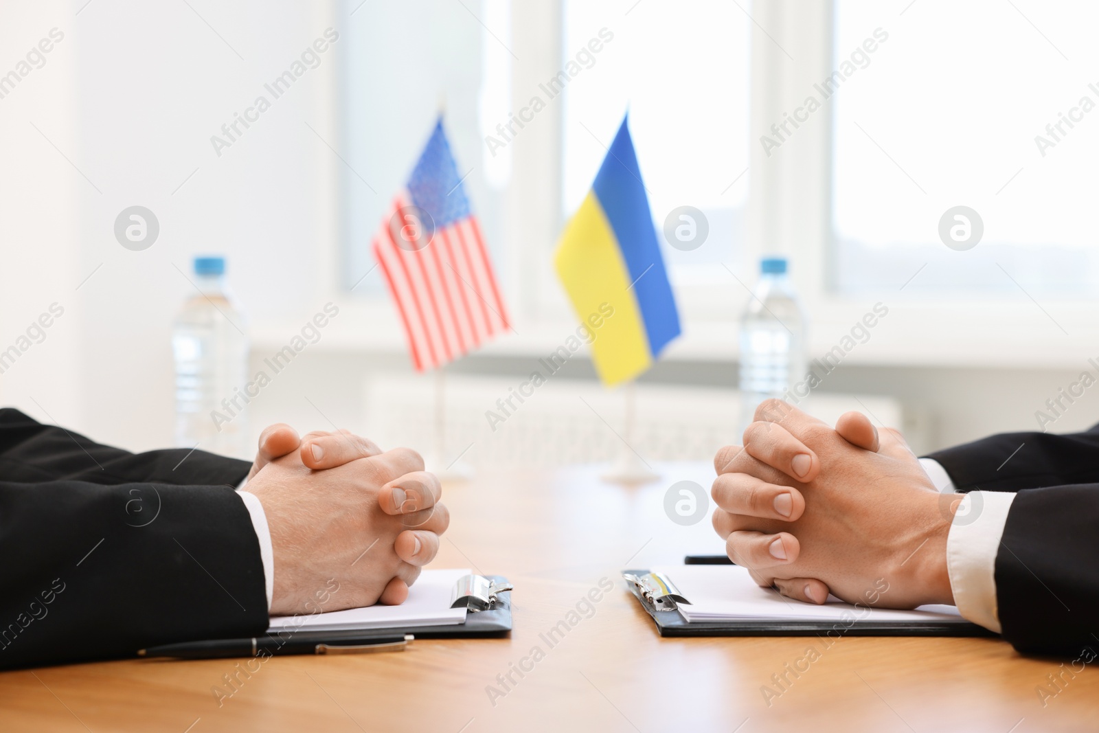 Photo of Diplomats negotiating during meeting at table indoors, closeup