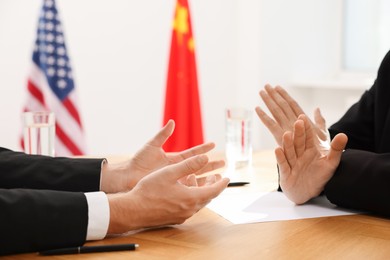 Diplomats negotiating during meeting at wooden table indoors, closeup