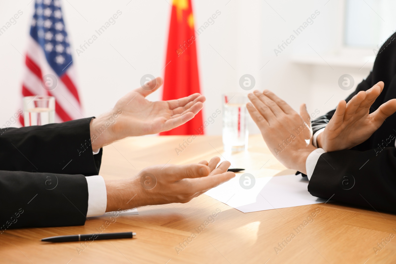 Photo of Diplomats negotiating during meeting at wooden table indoors, closeup