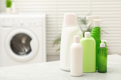 Photo of Different laundry detergents on light marble table in bathroom. Space for text