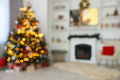 Photo of Blurred view of beautifully decorated Christmas tree near fireplace in room. Festive interior design