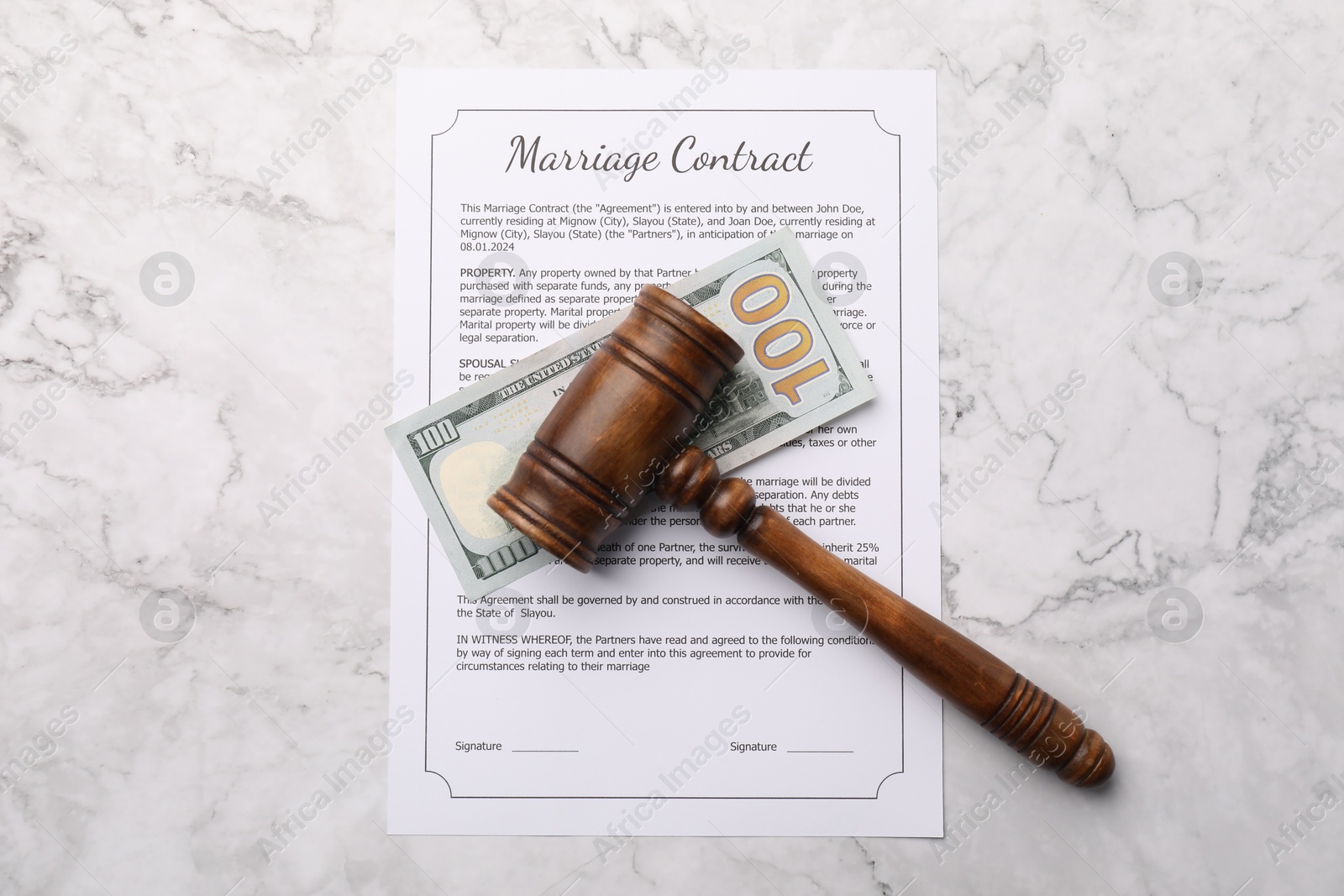 Photo of Marriage contract, dollar bill and gavel on white marble table, top view