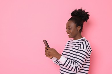 Photo of Happy woman with smartphone on pink background. Space for text