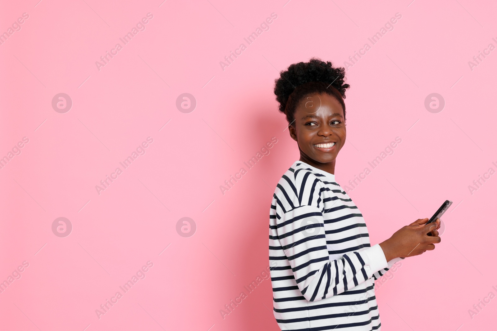 Photo of Happy woman with smartphone on pink background. Space for text