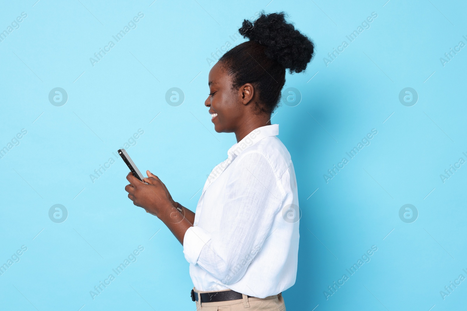 Photo of Happy woman with smartphone on light blue background