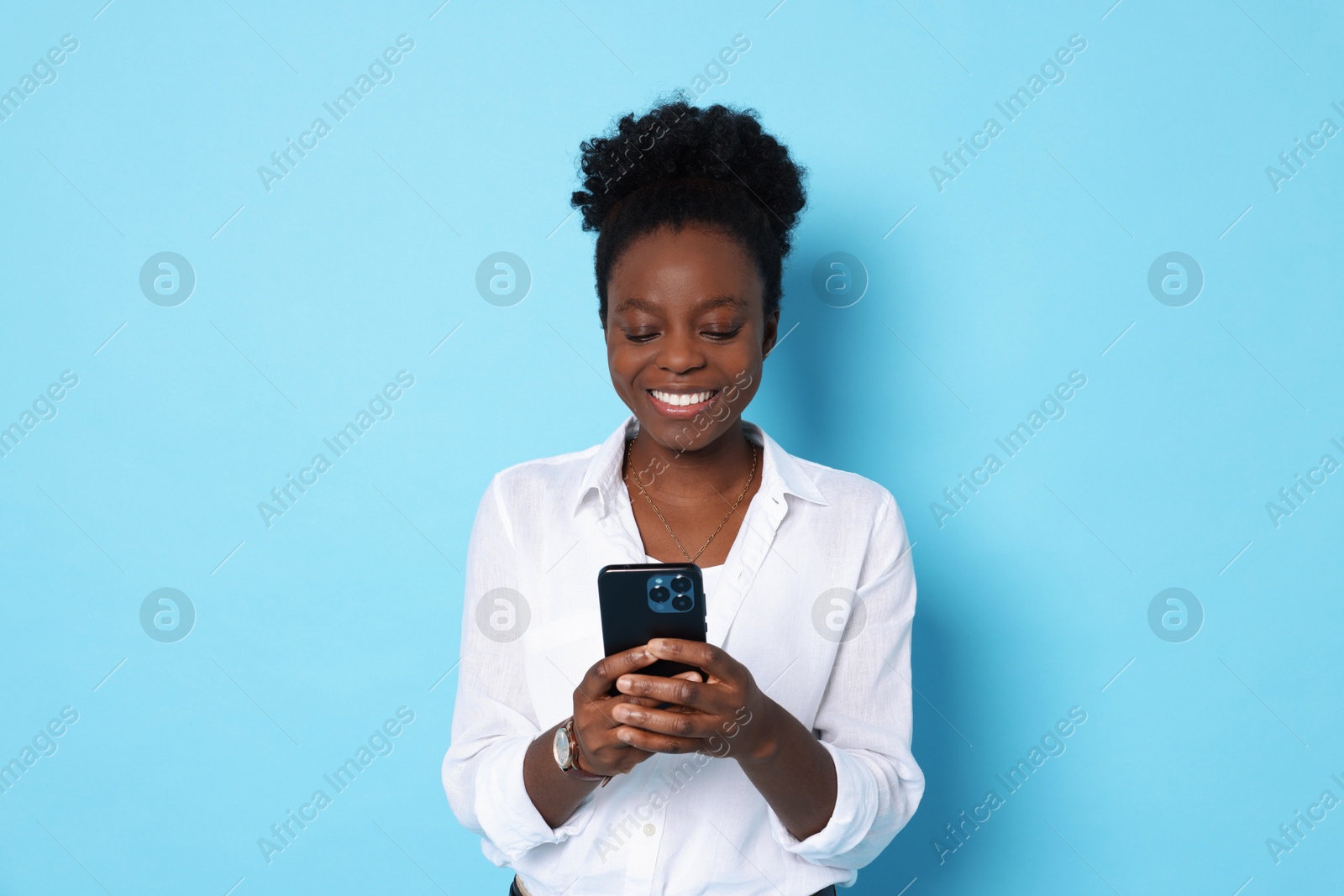 Photo of Happy woman with smartphone on light blue background