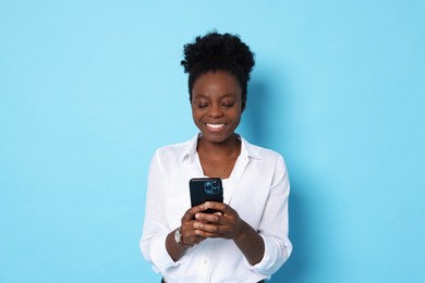 Photo of Happy woman with smartphone on light blue background