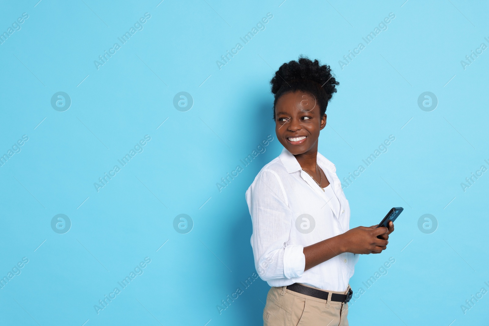 Photo of Happy woman with smartphone on light blue background. Space for text