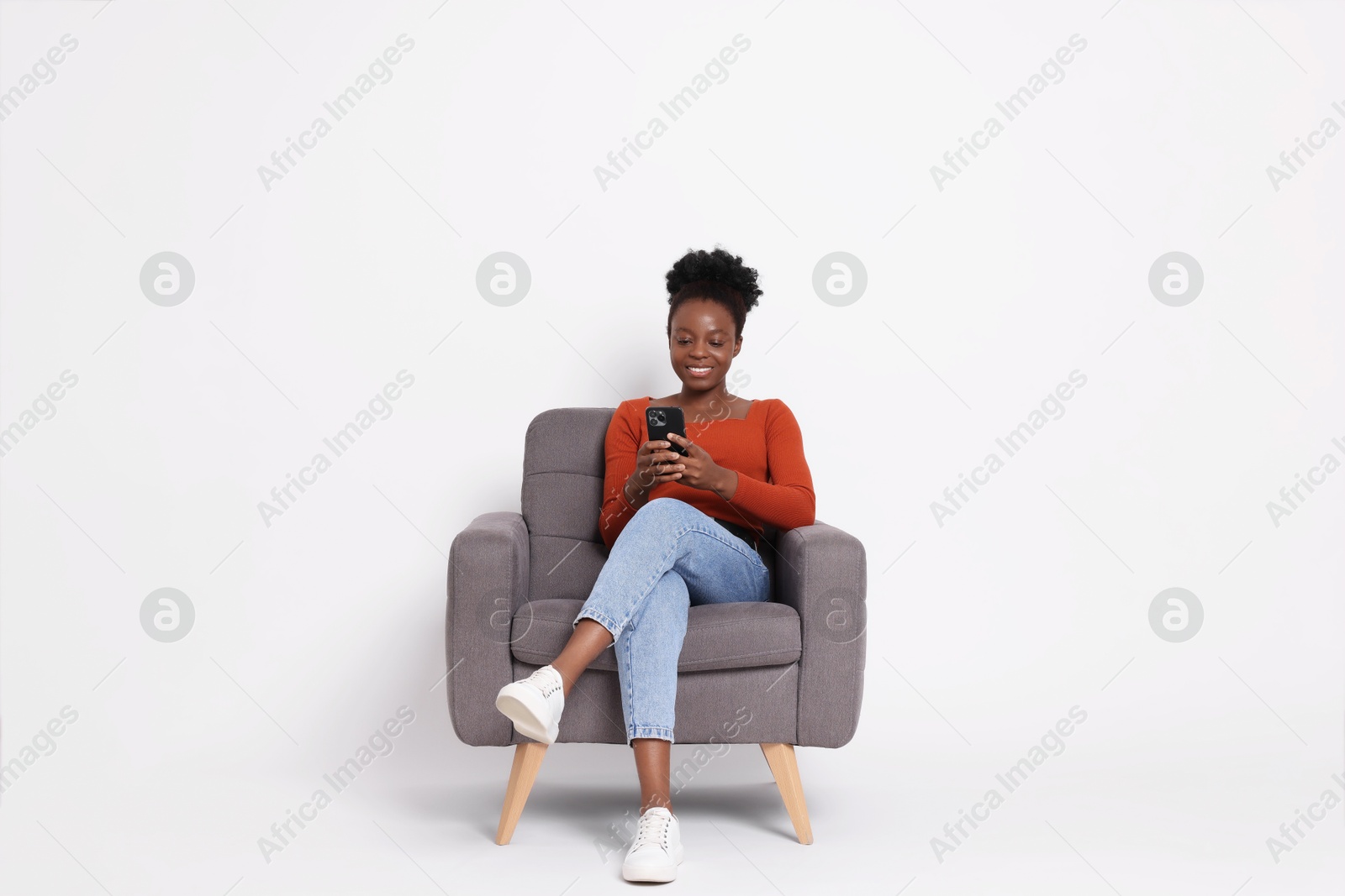 Photo of Smiling woman with smartphone sitting in armchair on white background. Space for text