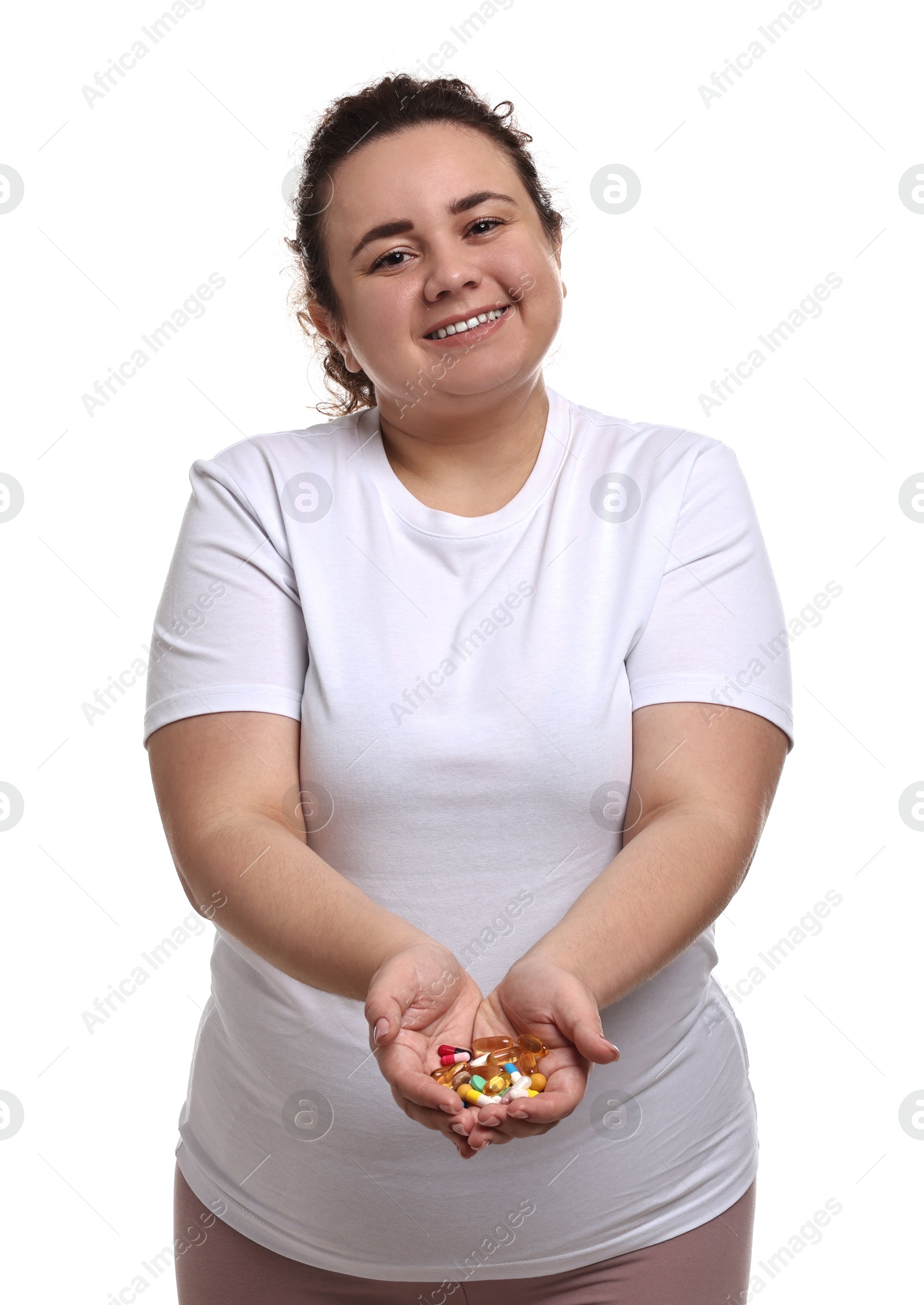 Photo of Happy plus size woman holding pile of weight loss supplements on white background