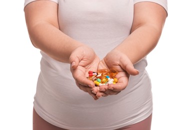 Photo of Plus size woman holding pile of weight loss supplements on white background, closeup