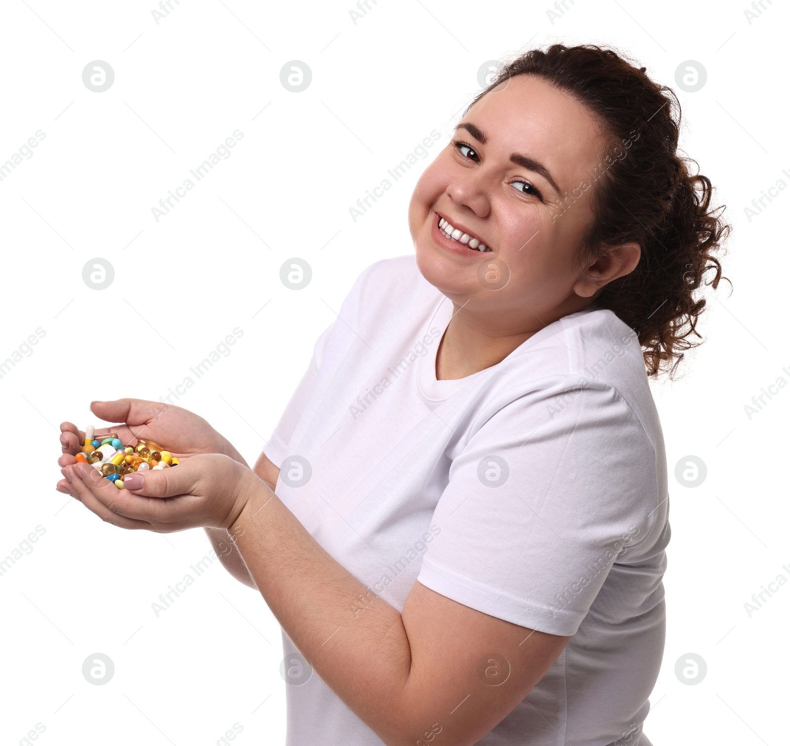 Photo of Happy plus size woman holding pile of weight loss supplements on white background