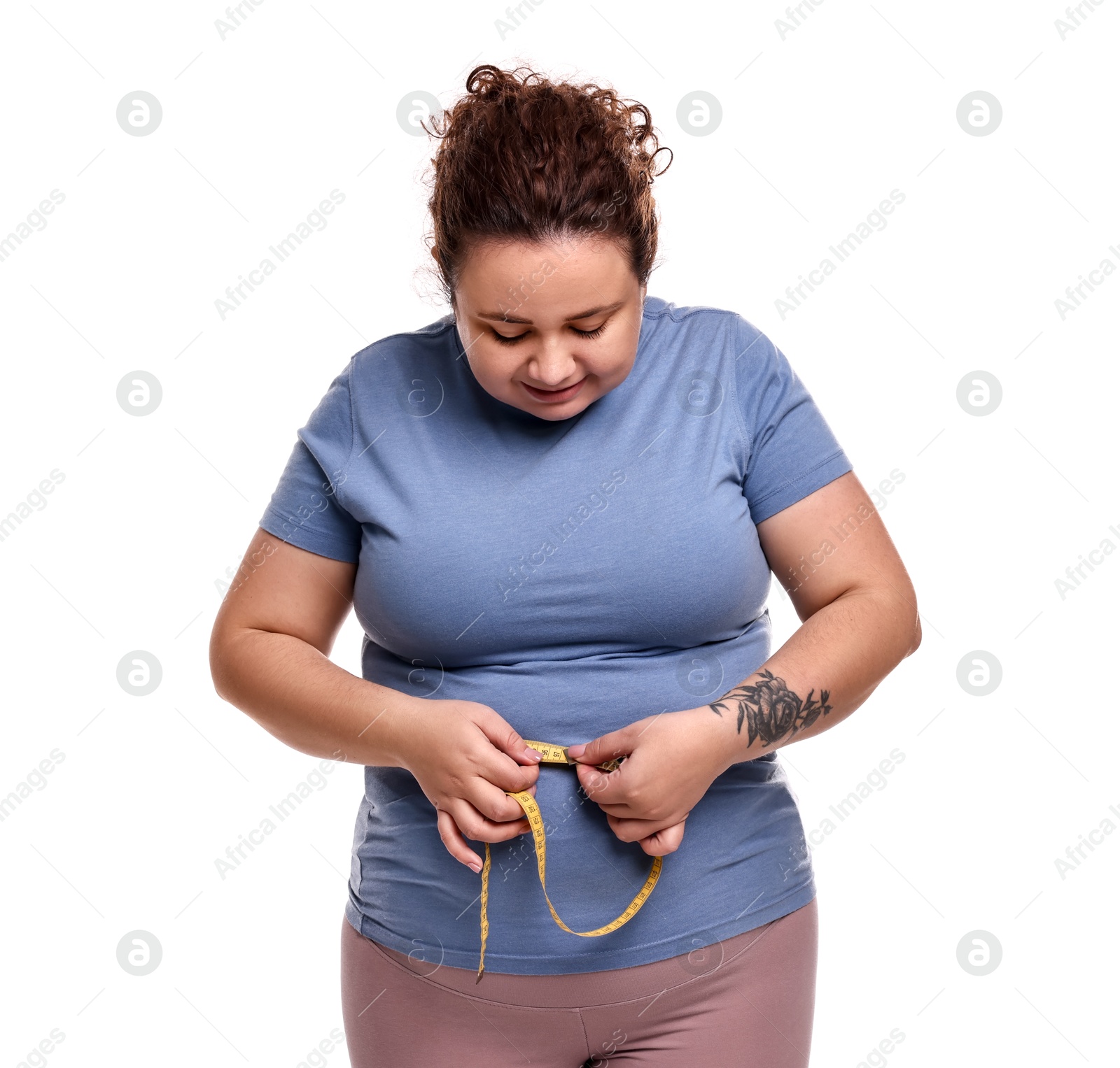 Photo of Weight loss. Plus size woman measuring waist with tape on white background