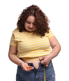 Photo of Plus size woman measuring waist with tape and holding pile of weight loss supplements on white background