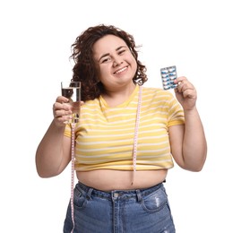 Photo of Happy plus size woman holding blister of weight loss supplements and glass of water on white background