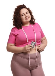 Photo of Happy plus size woman holding blister of weight loss supplements on white background