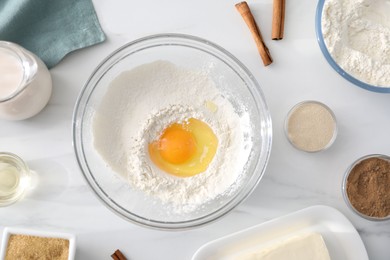 Photo of Making cinnamon rolls. Different ingredients for dough on white marble table, flat lay