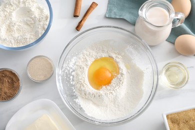 Photo of Making cinnamon rolls. Different ingredients for dough on white marble table, flat lay