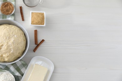 Photo of Making cinnamon rolls. Fresh dough in bowl and ingredients on light wooden table, flat lay. Space for text