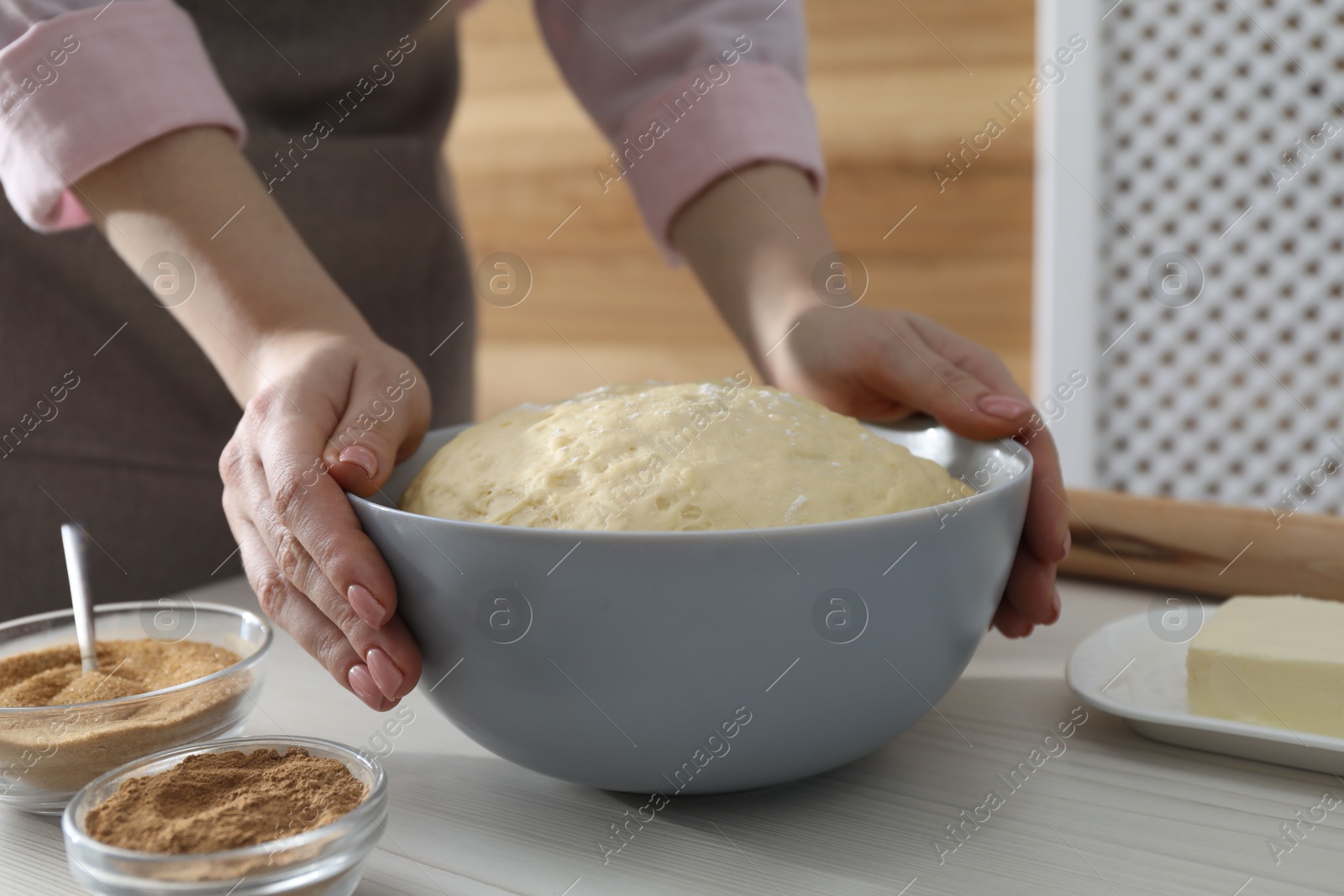 Photo of Making cinnamon rolls. Woman with dough at white wooden table, closeup