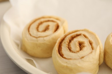 Photo of Uncooked cinnamon rolls in baking dish on table, closeup